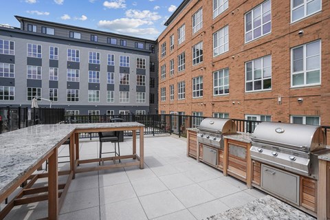 A patio with a grill and a table.