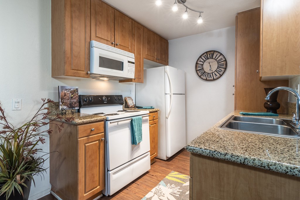 a kitchen with white appliances and granite counter tops and wooden cabinets