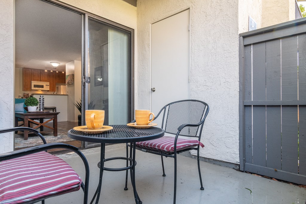 a patio with two chairs and a table with two cups on it