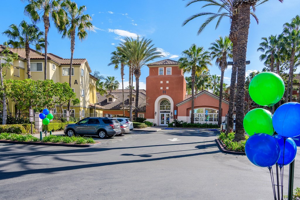 A street view with a car parked and a building with a red roof in the background.
