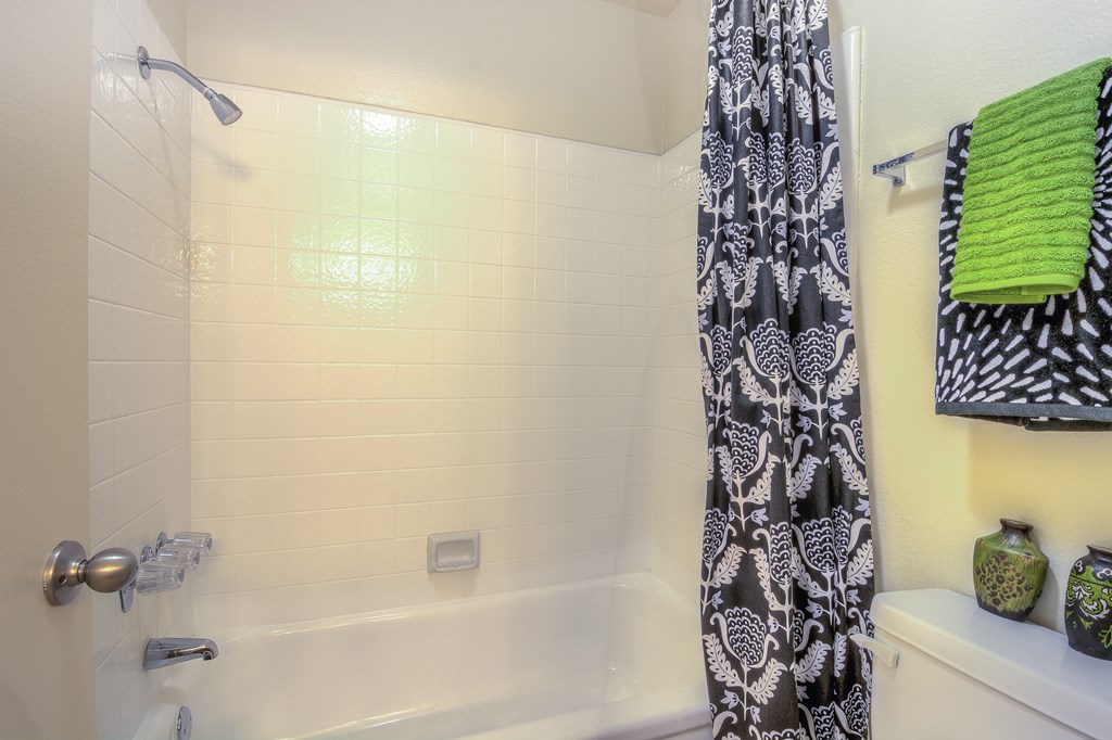A bathroom with a shower curtain and a green towel.