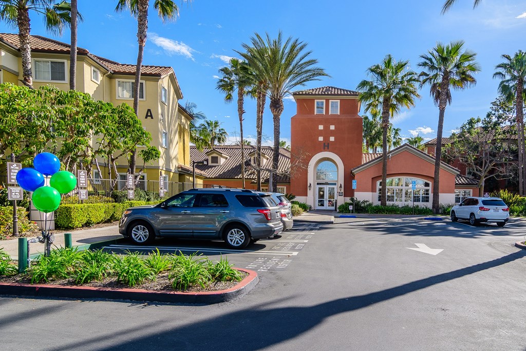 A sunny day at the park with a car and a building in the background.