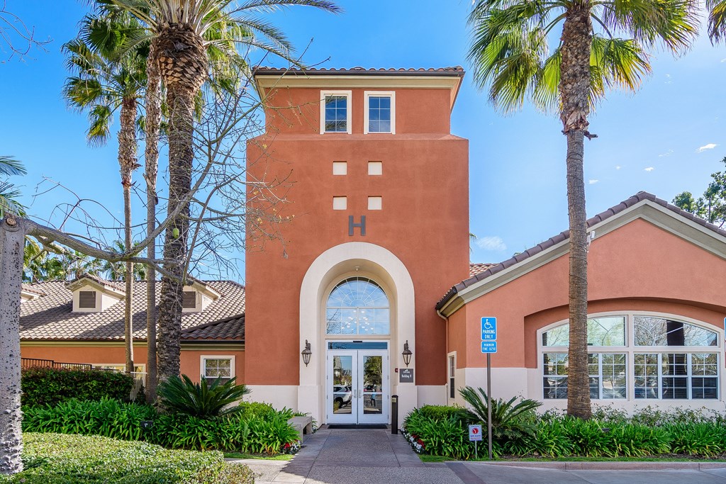 A building with a red brick tower and a white door is surrounded by palm trees.