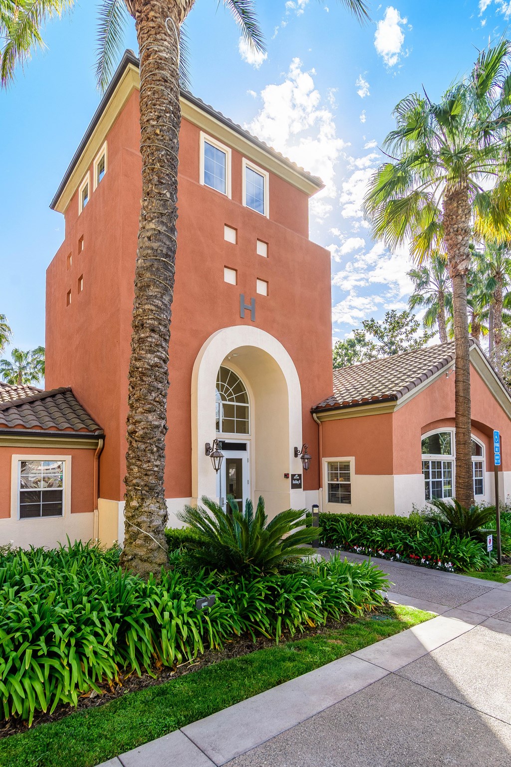 A red building with a palm tree in front.