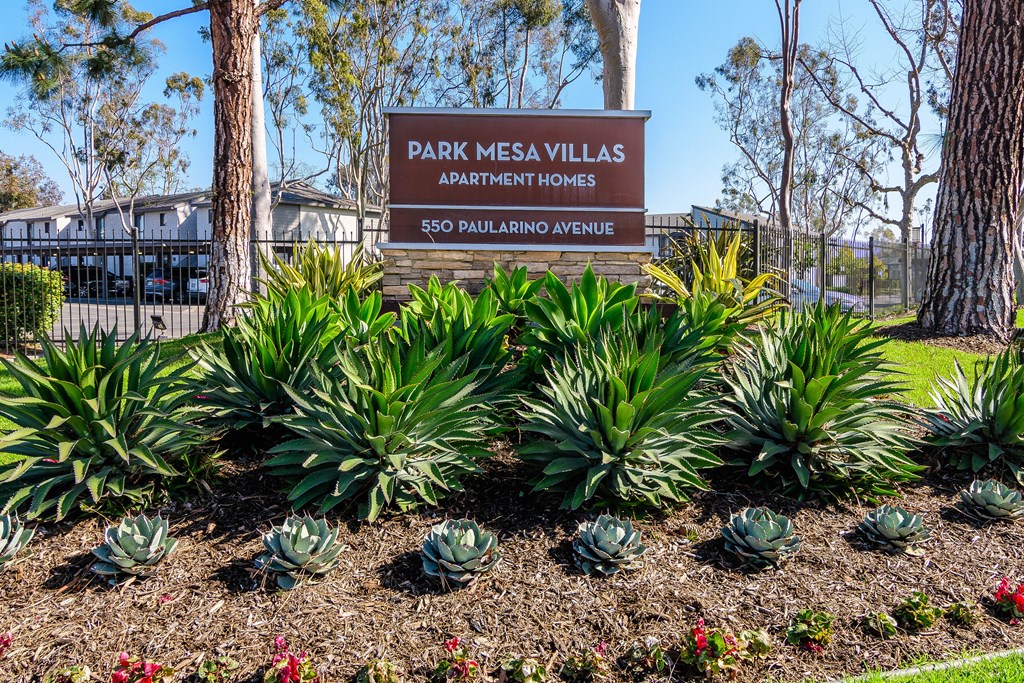 A sign for Park Mesa Villas Apartment Homes stands in front of a building.