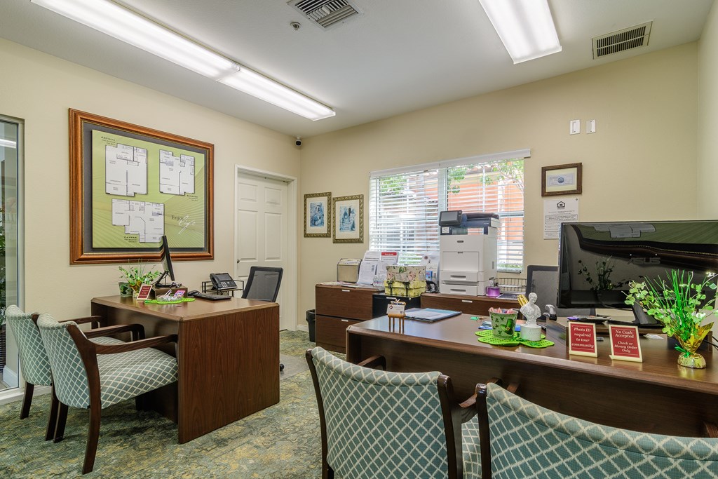A room with a desk and chairs and a bulletin board on the wall.
