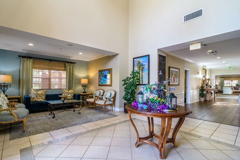 A living room with a couch, chairs, and a table with a vase of flowers on it.