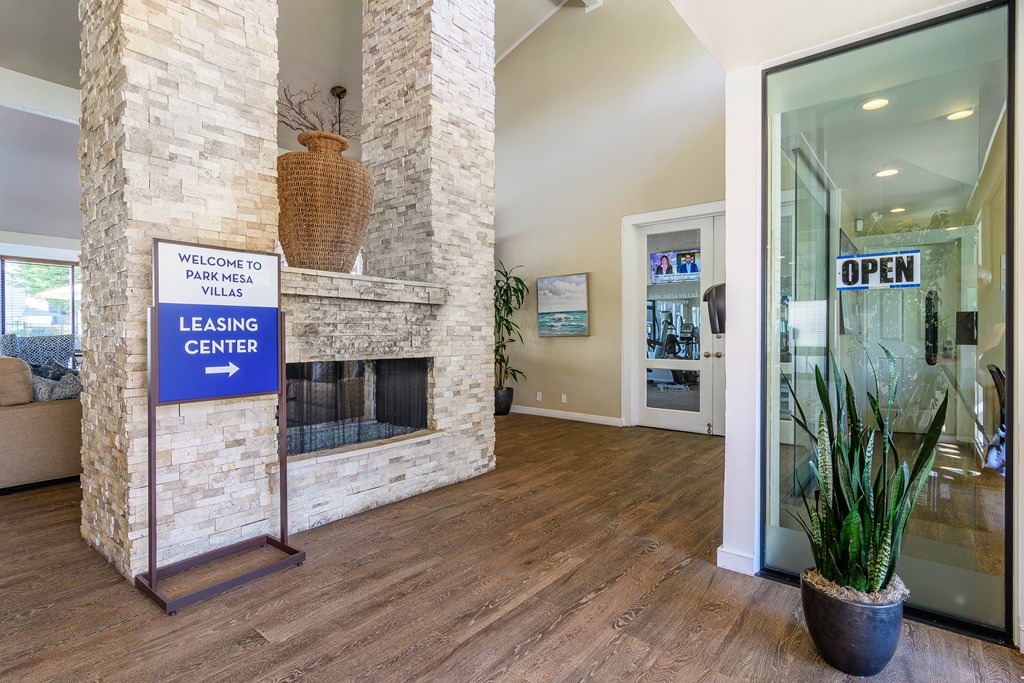 A leasing center sign is displayed in a spacious room with a stone fireplace.
