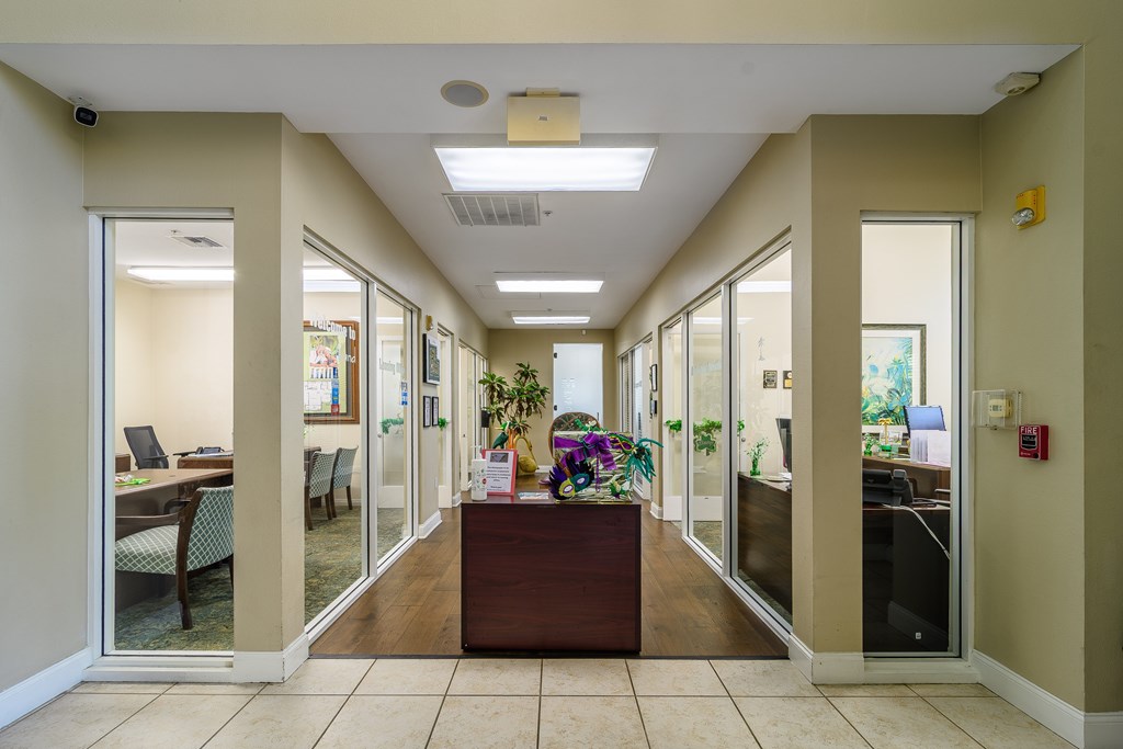 A hallway with a brown desk and glass doors.