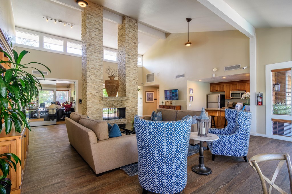 A living room with a stone fireplace and blue patterned chairs.