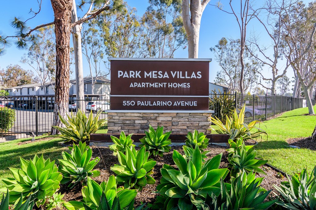 A sign for Park Mesa Villas Apartment Homes stands in front of a tree.