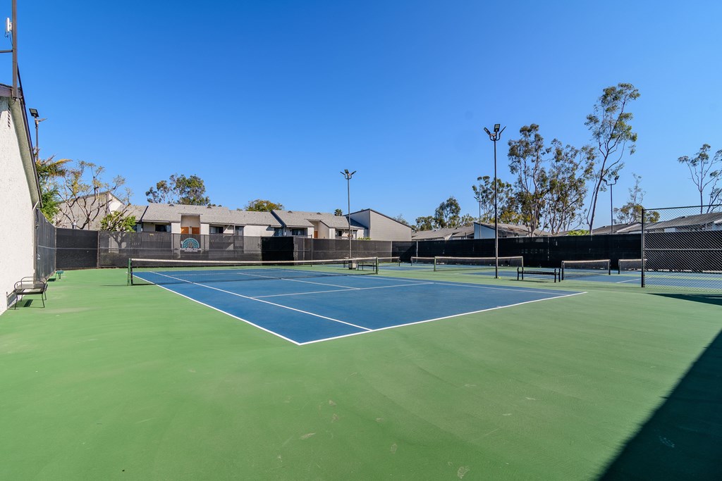 A tennis court with a blue surface and green edges.