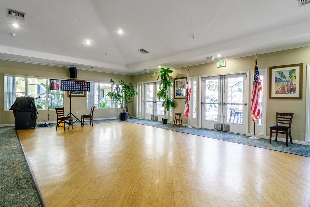 A room with wooden floors and a stage with chairs.