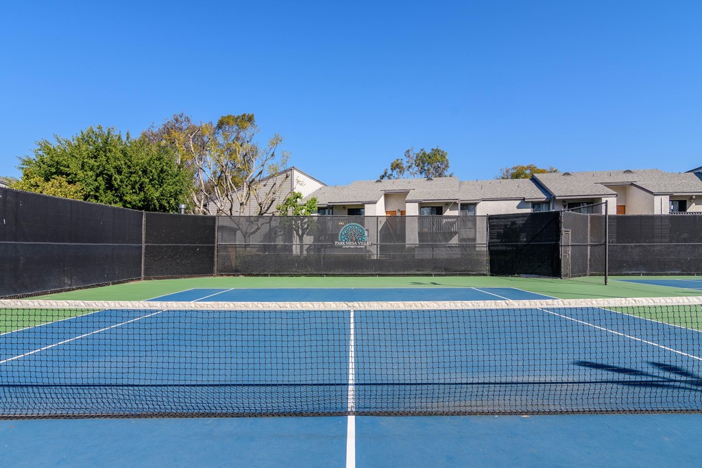 A tennis court with a blue surface and a black fence.