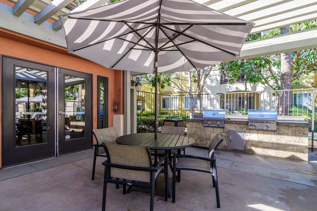 A patio with a table and chairs under an umbrella.