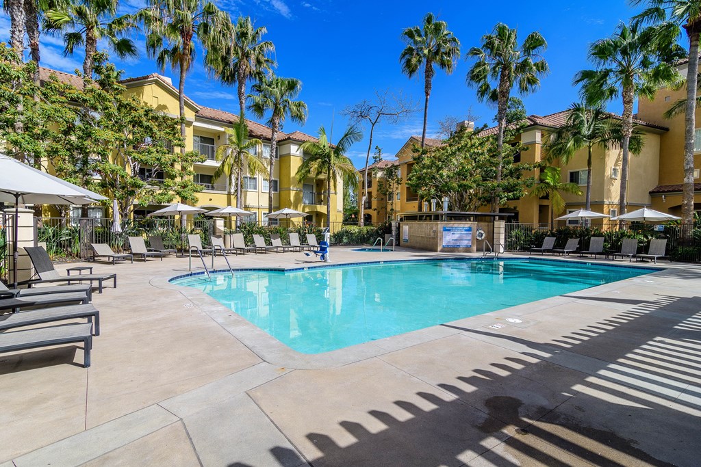A swimming pool surrounded by palm trees and lounge chairs.