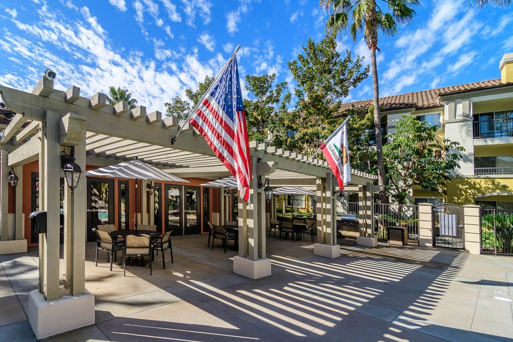 A patio area with a flag and a building in the background.