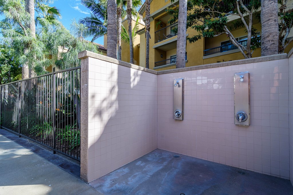 A pink wall with a black fence and a building in the background.