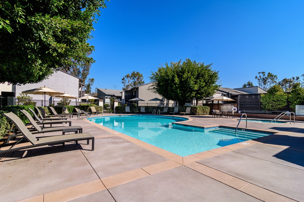 A swimming pool surrounded by lounge chairs and trees.