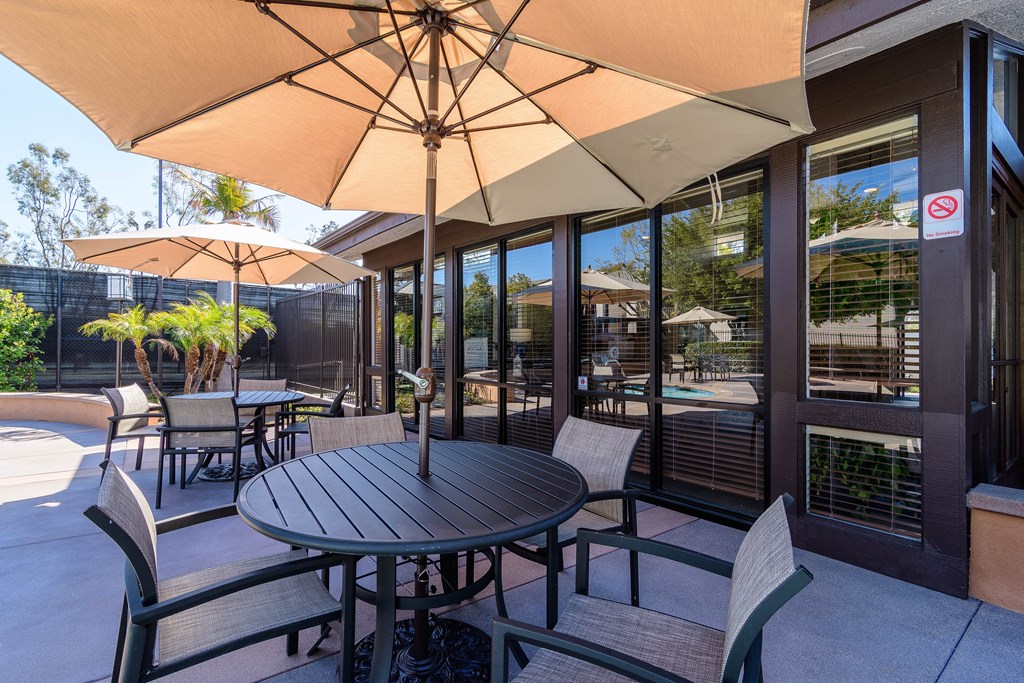 A patio with a table and chairs under an umbrella.