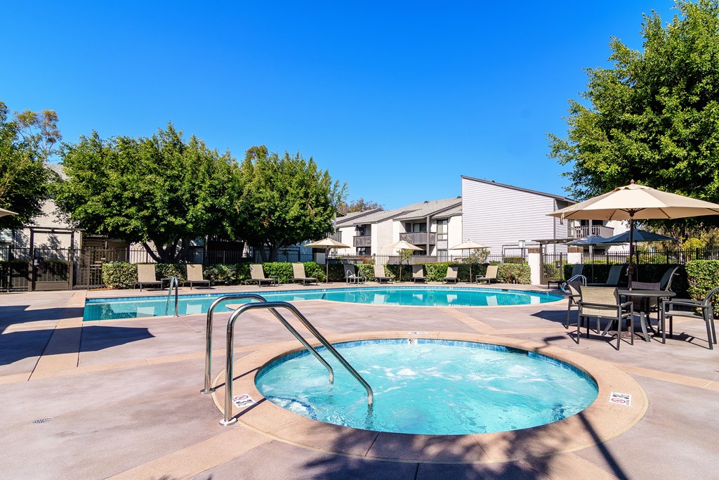A swimming pool surrounded by trees and chairs.