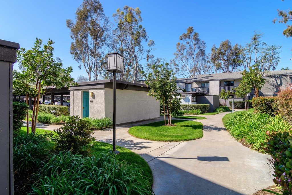 A sunny day in a residential area with a pathway and greenery.