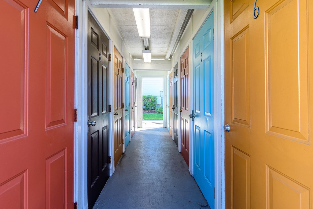 A hallway with doors on both sides leading to a grassy area.