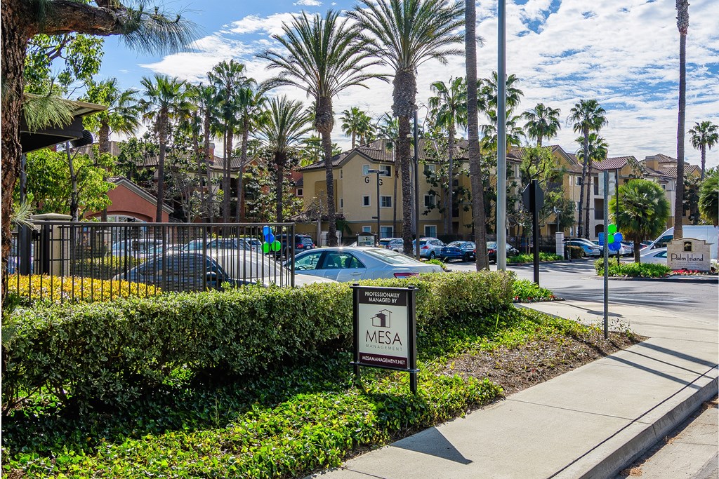 A sign for Mesa stands in front of a hedge.