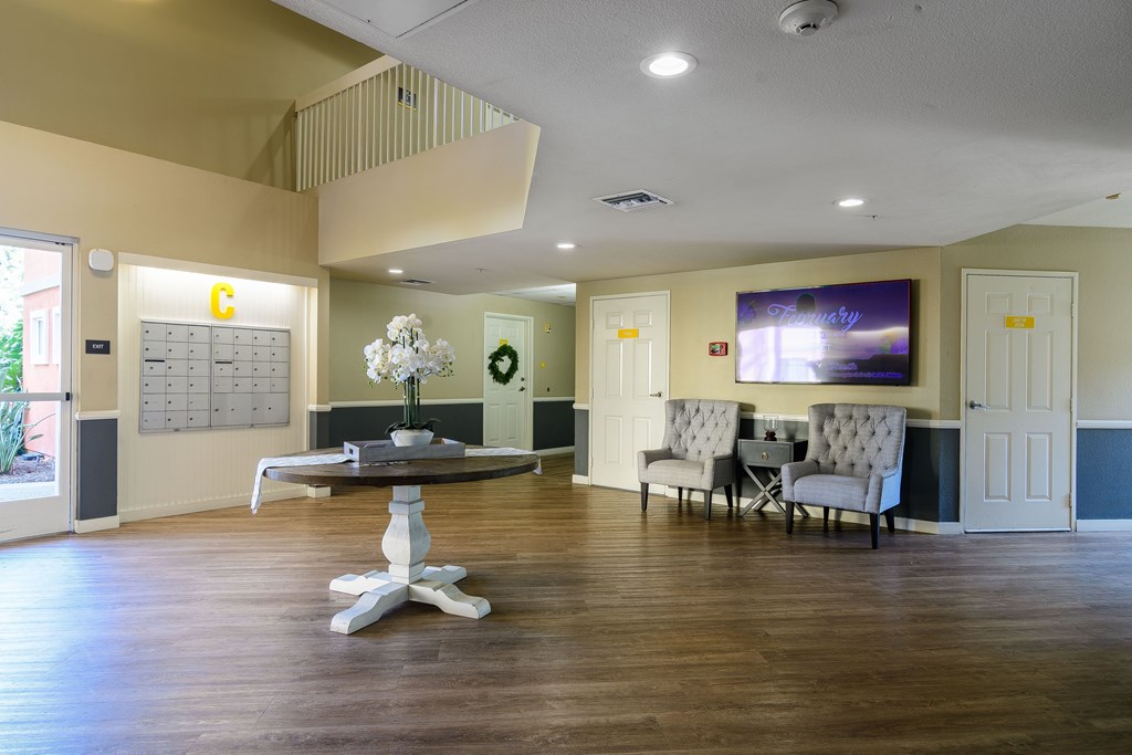 A large room with a wooden floor and a round table with a flower arrangement on it.