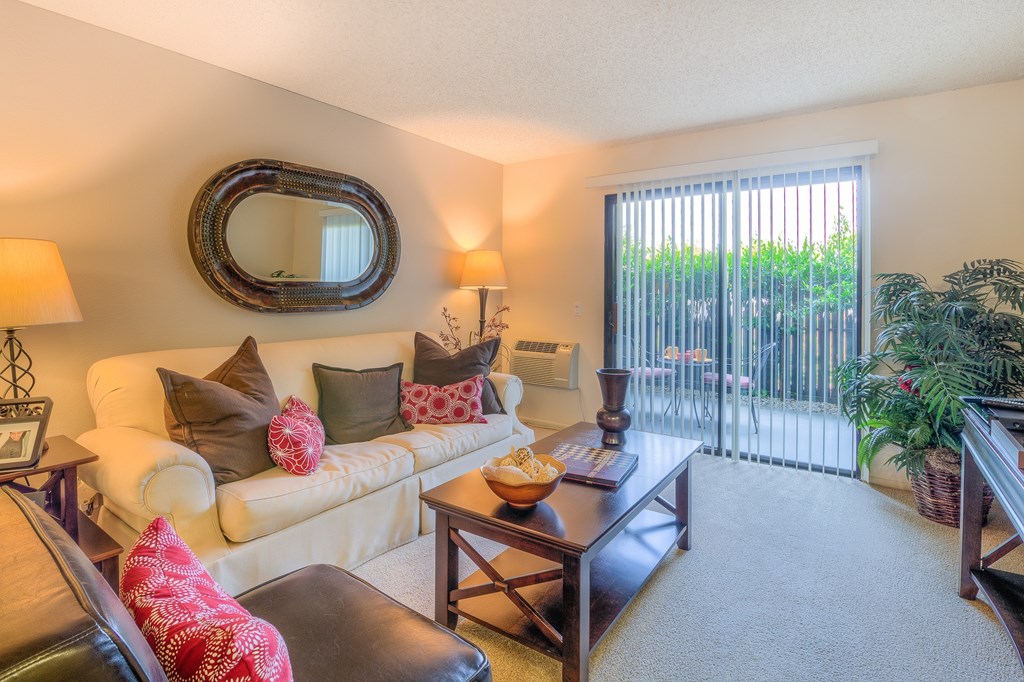 A living room with a white couch, a brown leather chair, and a wooden coffee table.