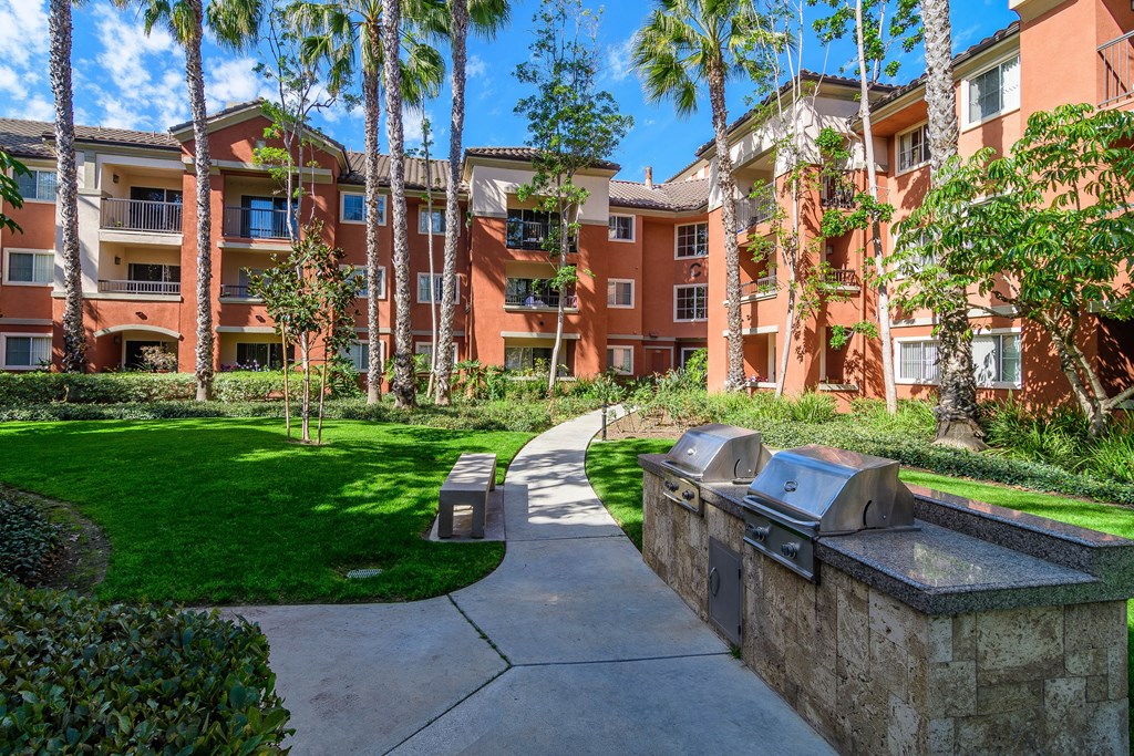 A sunny day at a residential complex with a pathway and grassy area.