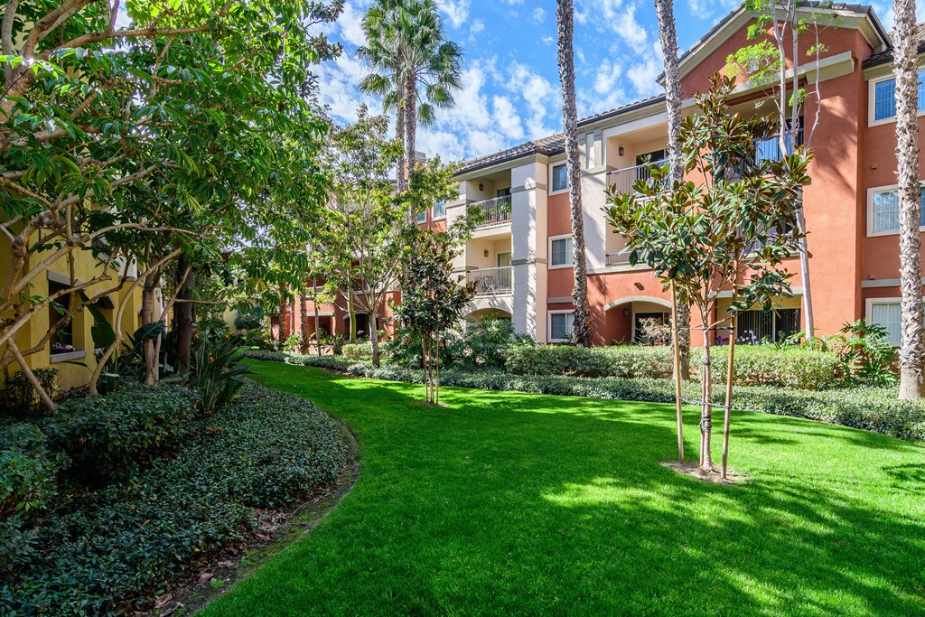 A green lawn in front of a building with trees.