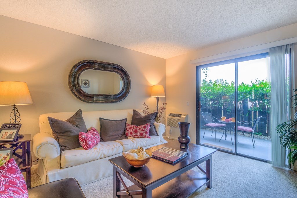A living room with a white couch, a coffee table, and a large mirror on the wall.