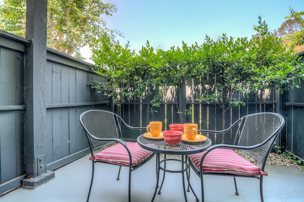 A patio with a table and chairs and a fence.