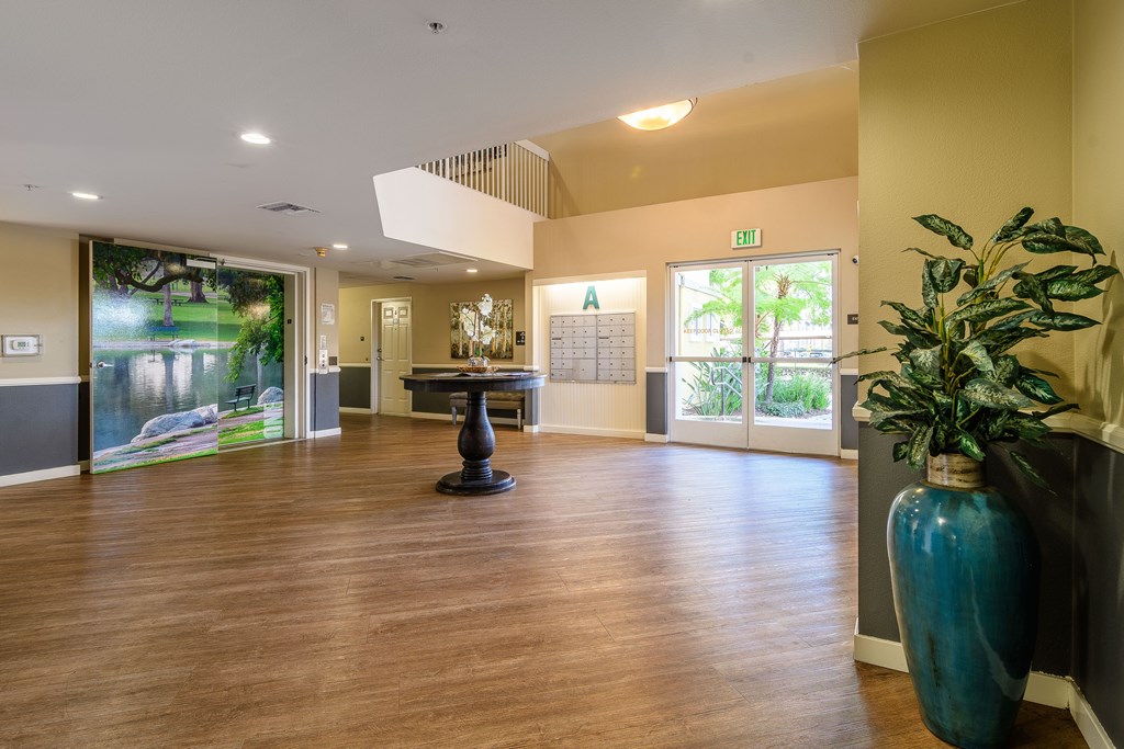 A large room with a wooden floor and a blue vase on the right side.