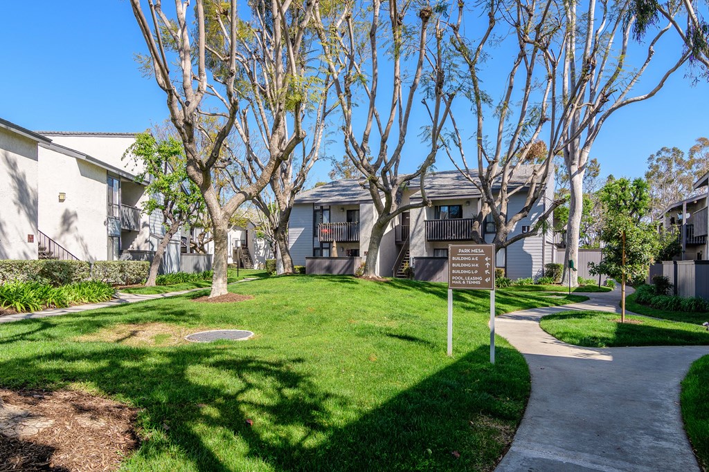 A sign in a grassy area in front of a building.