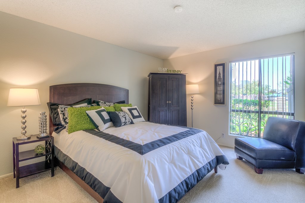 A bedroom with a large bed and a blue chair.
