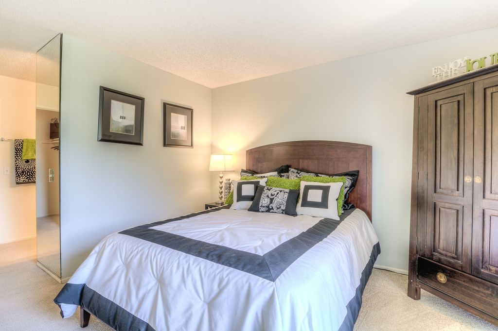 A bedroom with a large bed and a wooden cabinet.