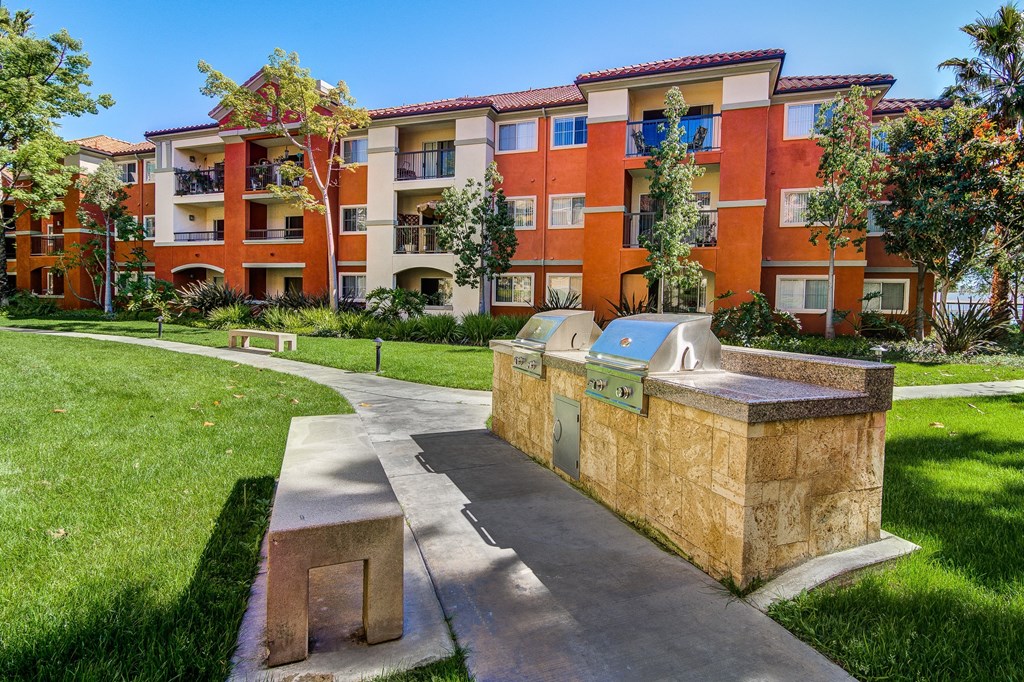 a pathway leading to an apartment building with a fountain
