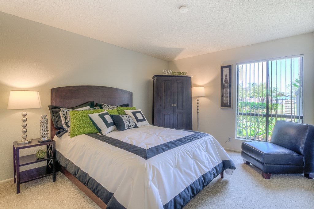 A bedroom with a large bed and a blue chair.
