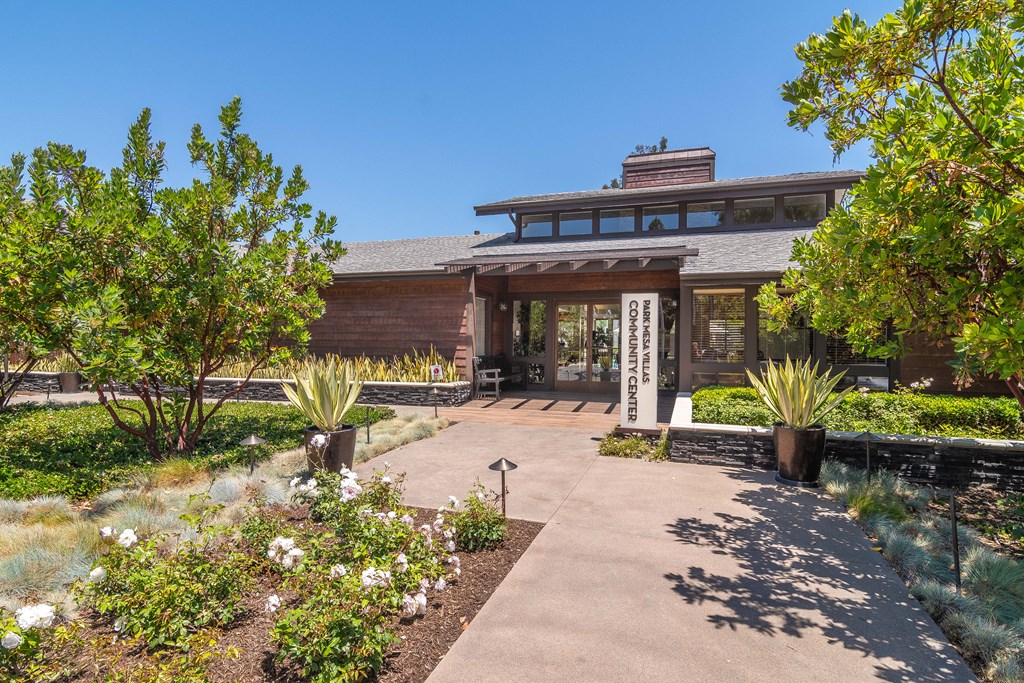 the front entrance of a brick building with a walkway and plants