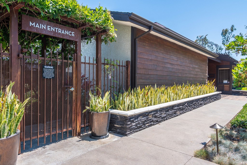 the entrance to the main entrance of a building with a fence and plants