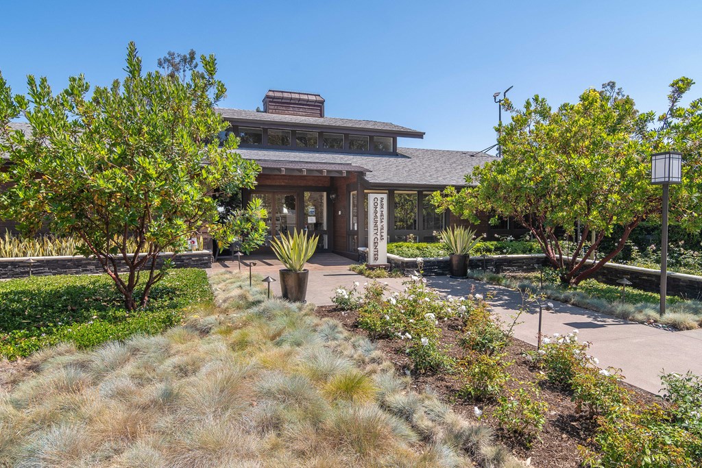 the front of the house has a walkway with plants and trees