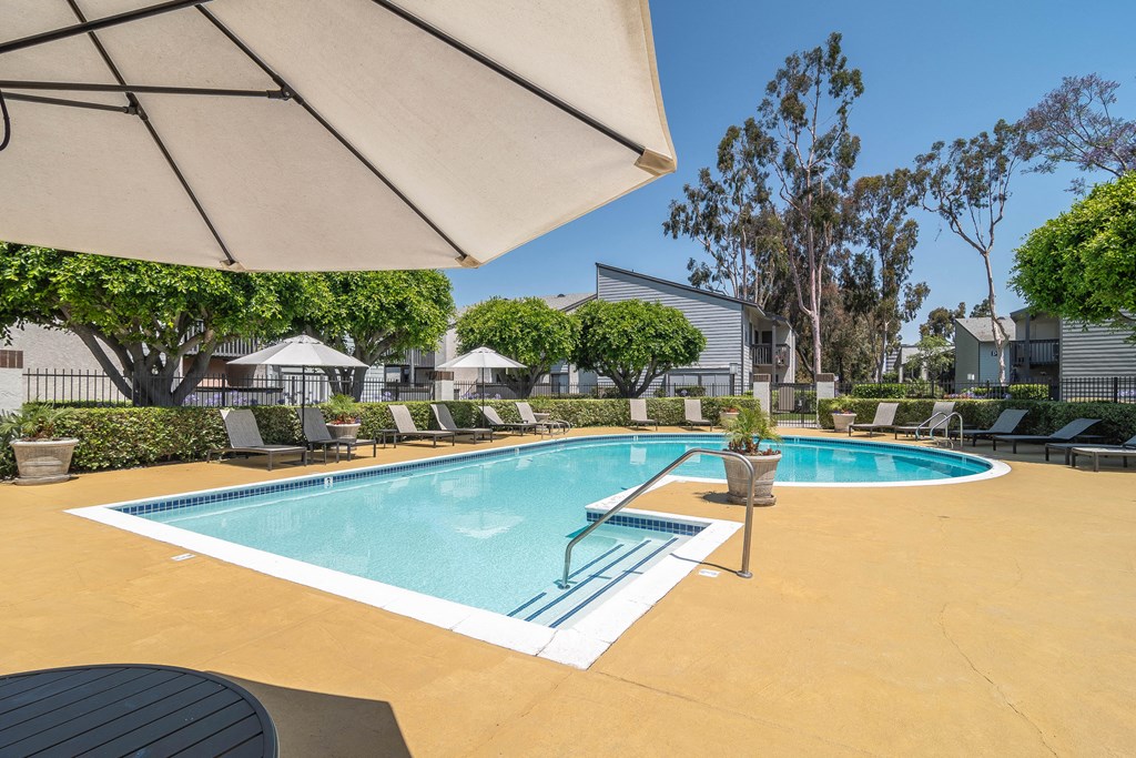 a swimming pool with chairs and an umbrella next to it