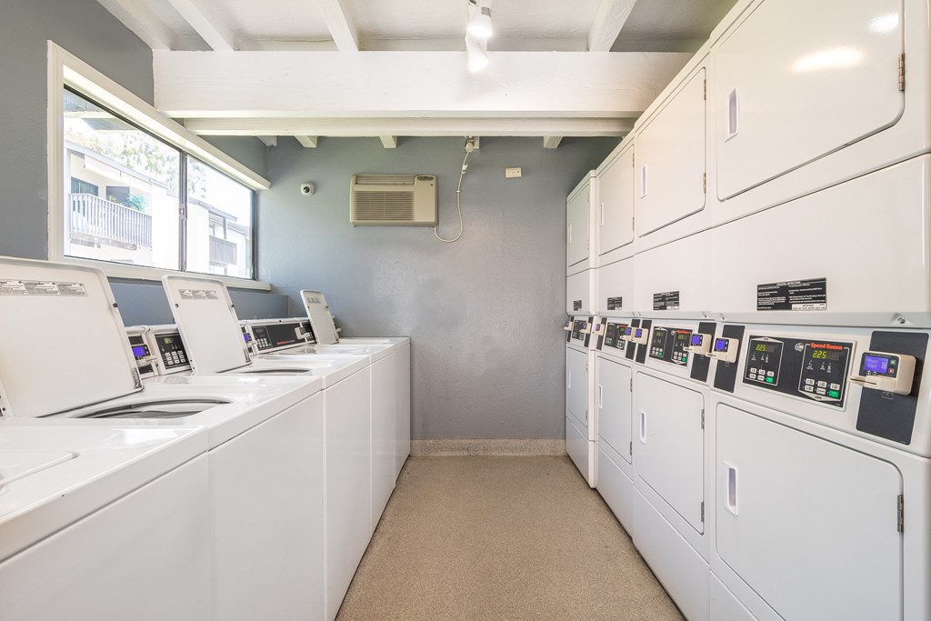 a laundry room with white appliances and counters and a window