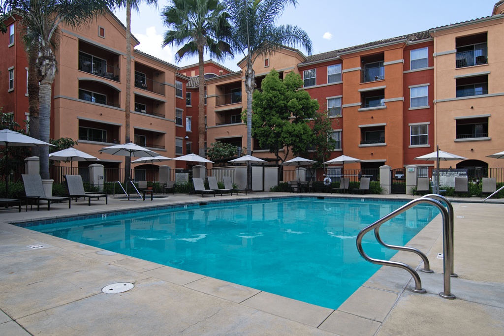 A swimming pool surrounded by apartment buildings and palm trees.