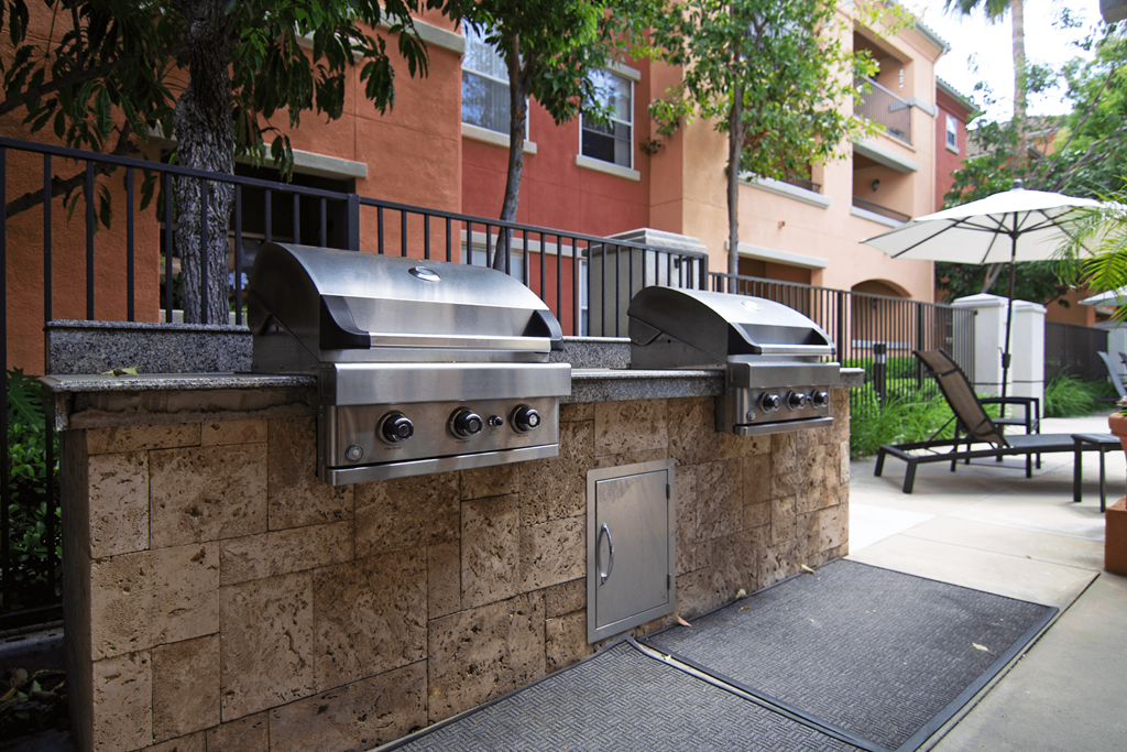 A wall of outdoor grills is in front of a building.