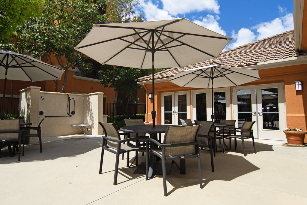 A patio with tables and chairs under umbrellas.