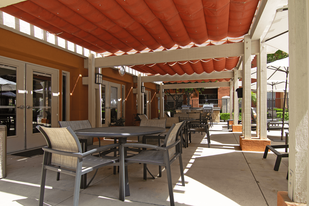 A patio with tables and chairs under a red roof.