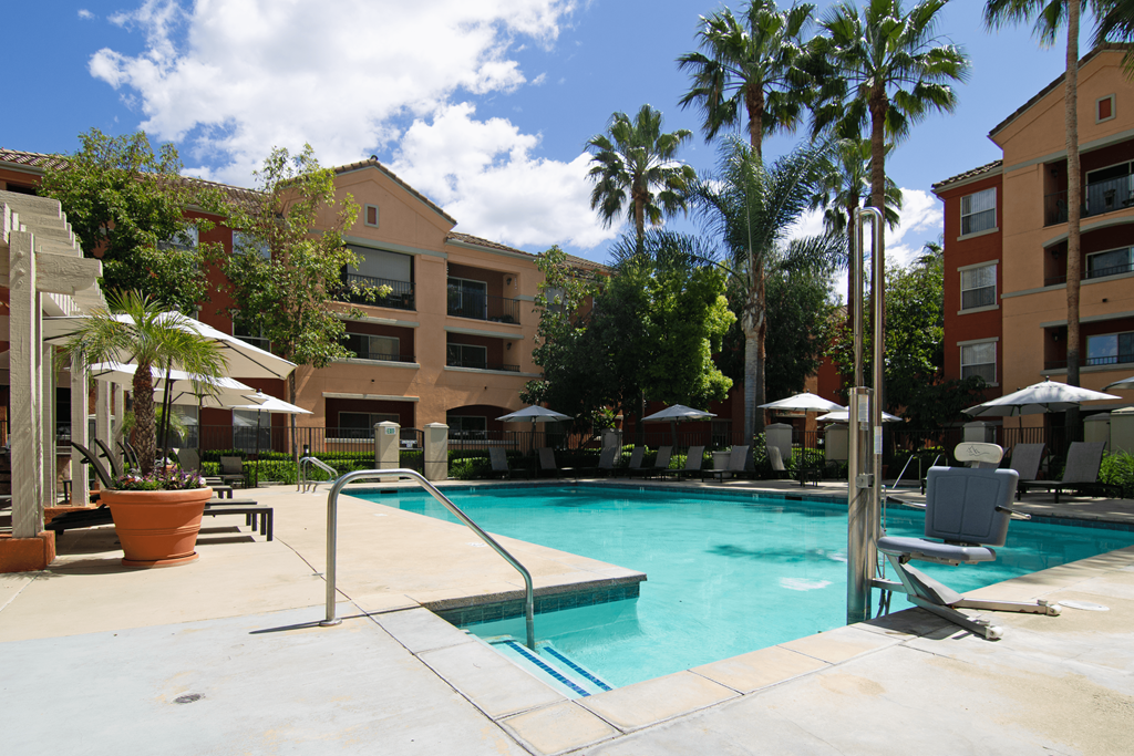 A pool surrounded by palm trees and umbrellas.